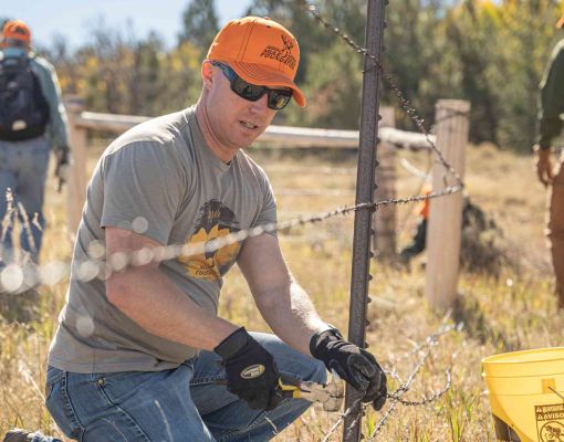 Volunteer repairing fence during habitat restoration work for Mule Deer Foundation.