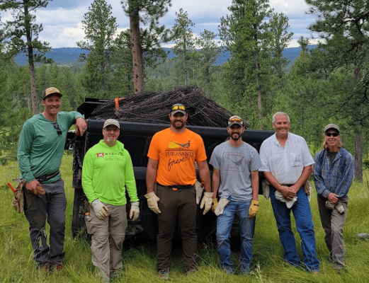 Group photo of volunteers engaged in conservation work in a forested area.