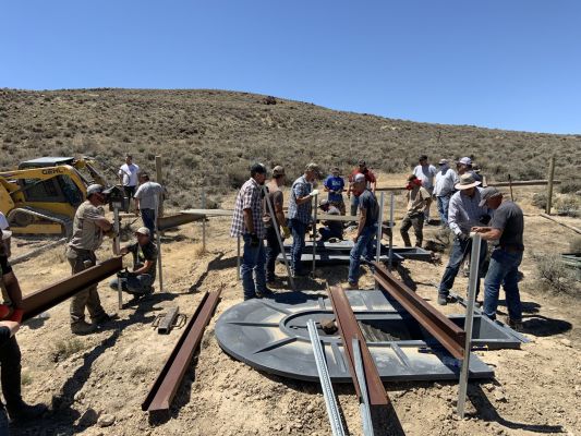 Group of volunteers constructing a fence in sagebrush habitat.