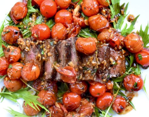 Grilled venison steak garnished with roasted cherry tomatoes.