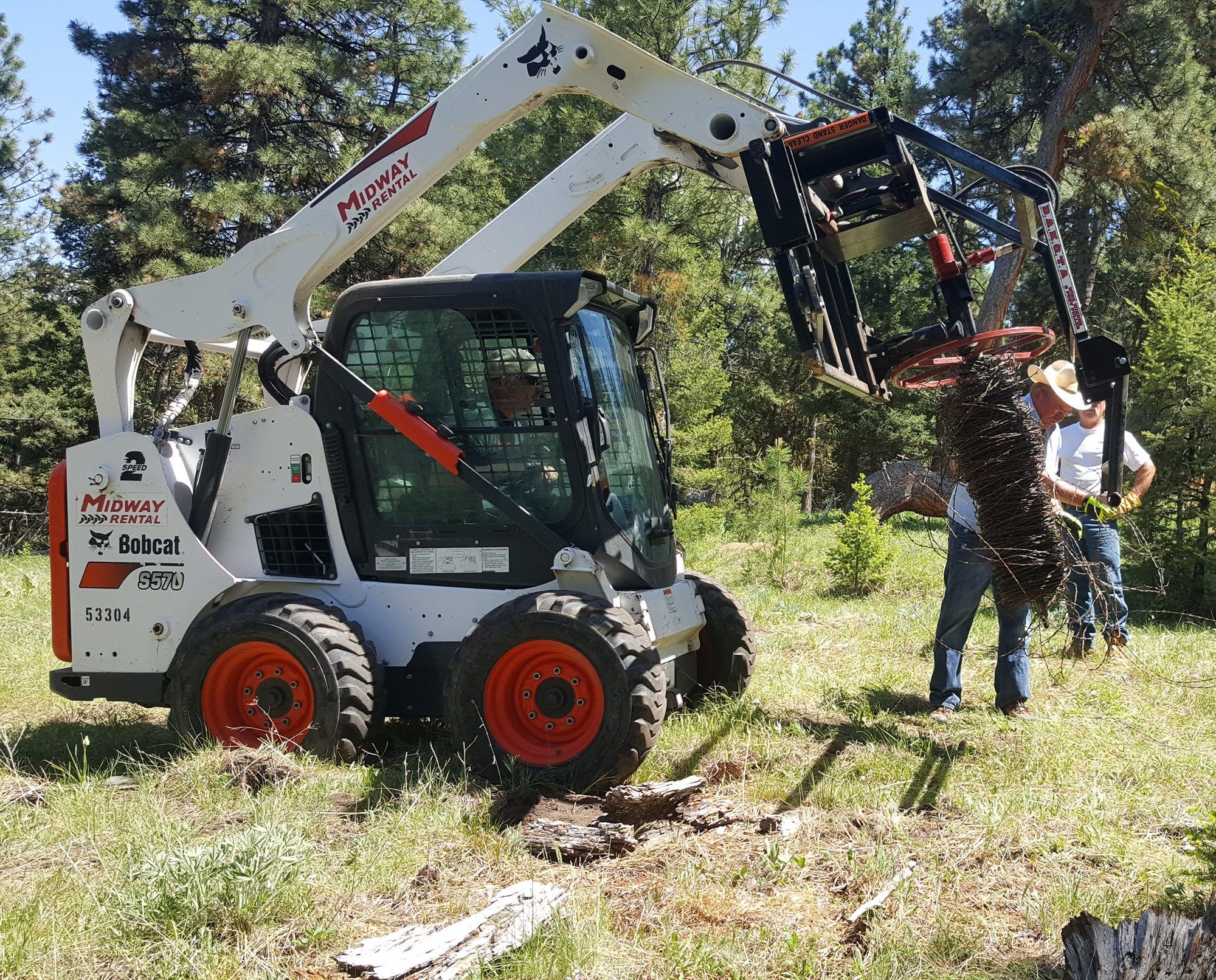 Volunteers using a Bobcat for habitat restoration.