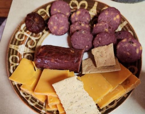 Plate of assorted snacks including sausage, cheese, and crackers.