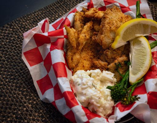 Plate of fried fish with coleslaw and lemon slices