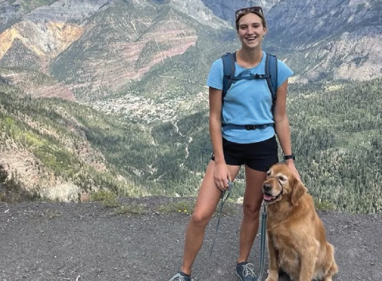 Hiker with a golden retriever enjoying a mountain view.