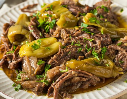 Pulled venison served with peppers and herbs on a plate.