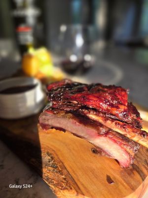 Delicious smoked ribs presented on a wooden board with sides.