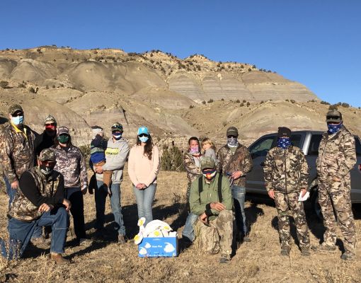 Group of volunteers in camouflage gear in a mountain setting.