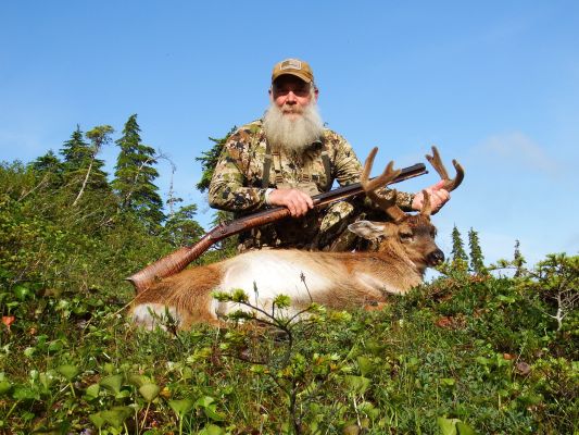Hunter with mule deer buck in a forest setting