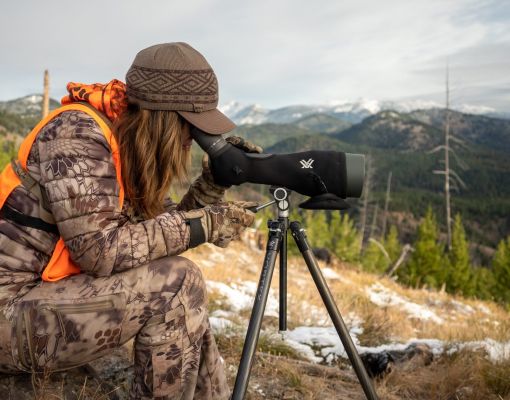 Hunter observing mountains through a spotting scope.