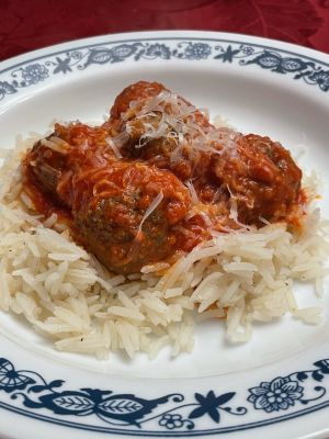 Plate of meatballs in tomato sauce served over rice