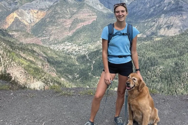Hiker with a golden retriever enjoying a mountain view.