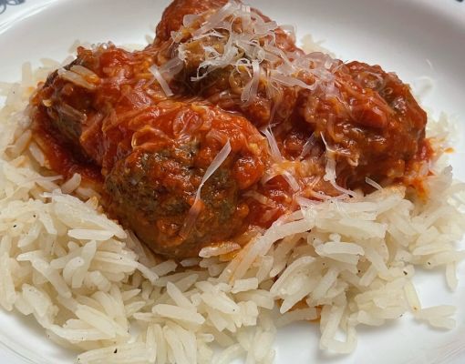 Plate of meatballs in tomato sauce served over rice