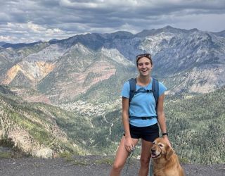 Hiker with a golden retriever enjoying a mountain view.