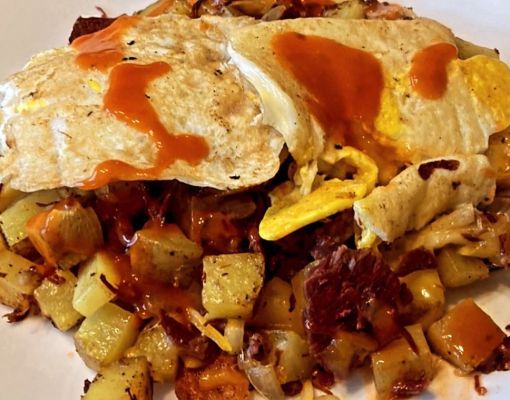 Plate of hash browns topped with eggs and sauce