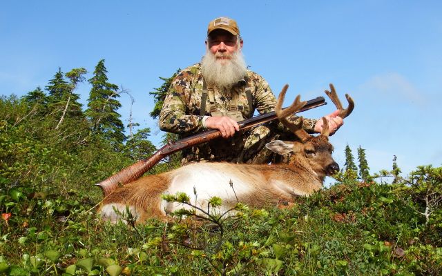 Hunter with mule deer buck in a forest setting