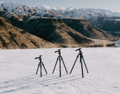 Tripods on snow with a mountain landscape in the background.