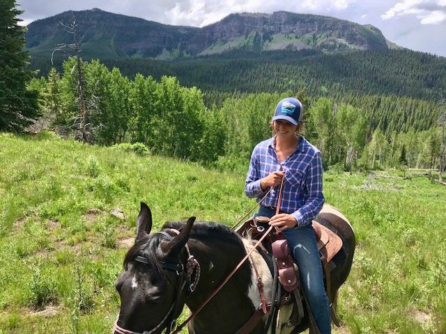 Individual riding a horse in a mountainous area.