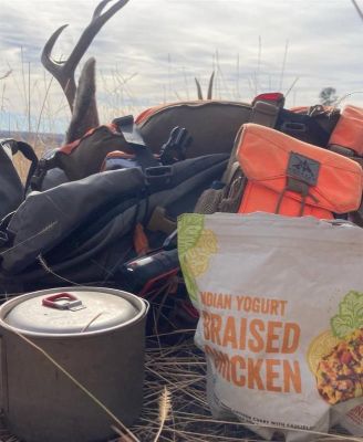 Hunting gear and cookware in a field with a mule deer antler.