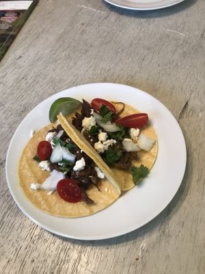 Tacos topped with vegetables and cheese on a white plate.