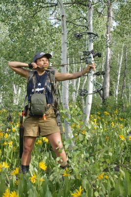 Woman practicing archery in a flower-filled forest