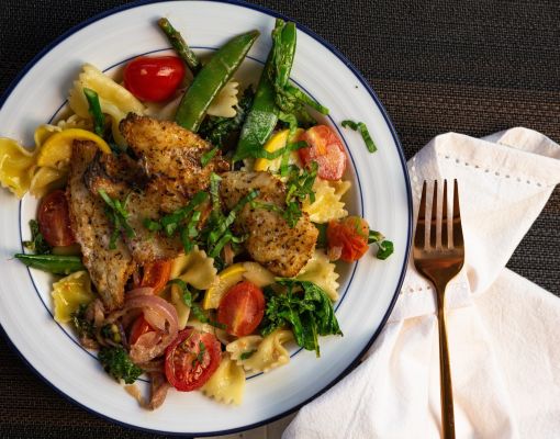 Delicious pasta dish with grilled fish and mixed vegetables.