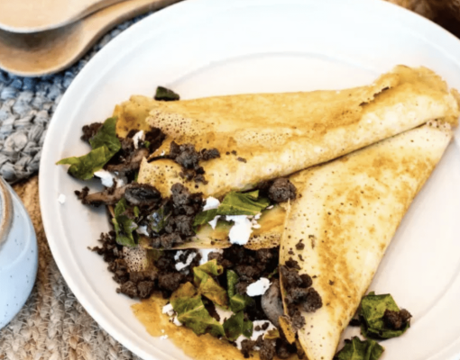 Savory crepe filled with meat and greens on a plate.
