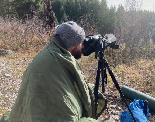 Man using spotting scope in the forest.