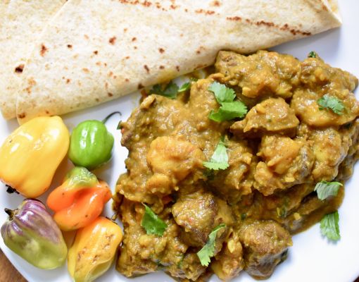 Cooked meat with colorful peppers and flatbread on a plate.