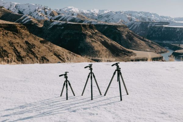 Tripods on snow with a mountain landscape in the background.