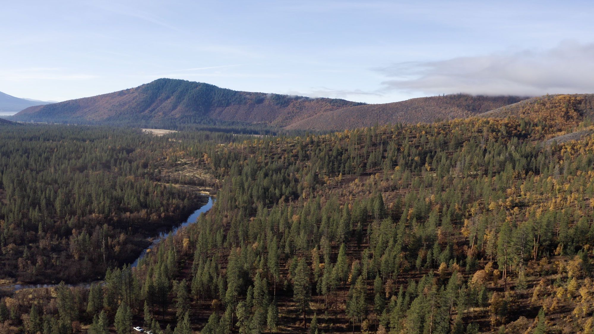 Aerial view of a forested mountain area with a winding river.