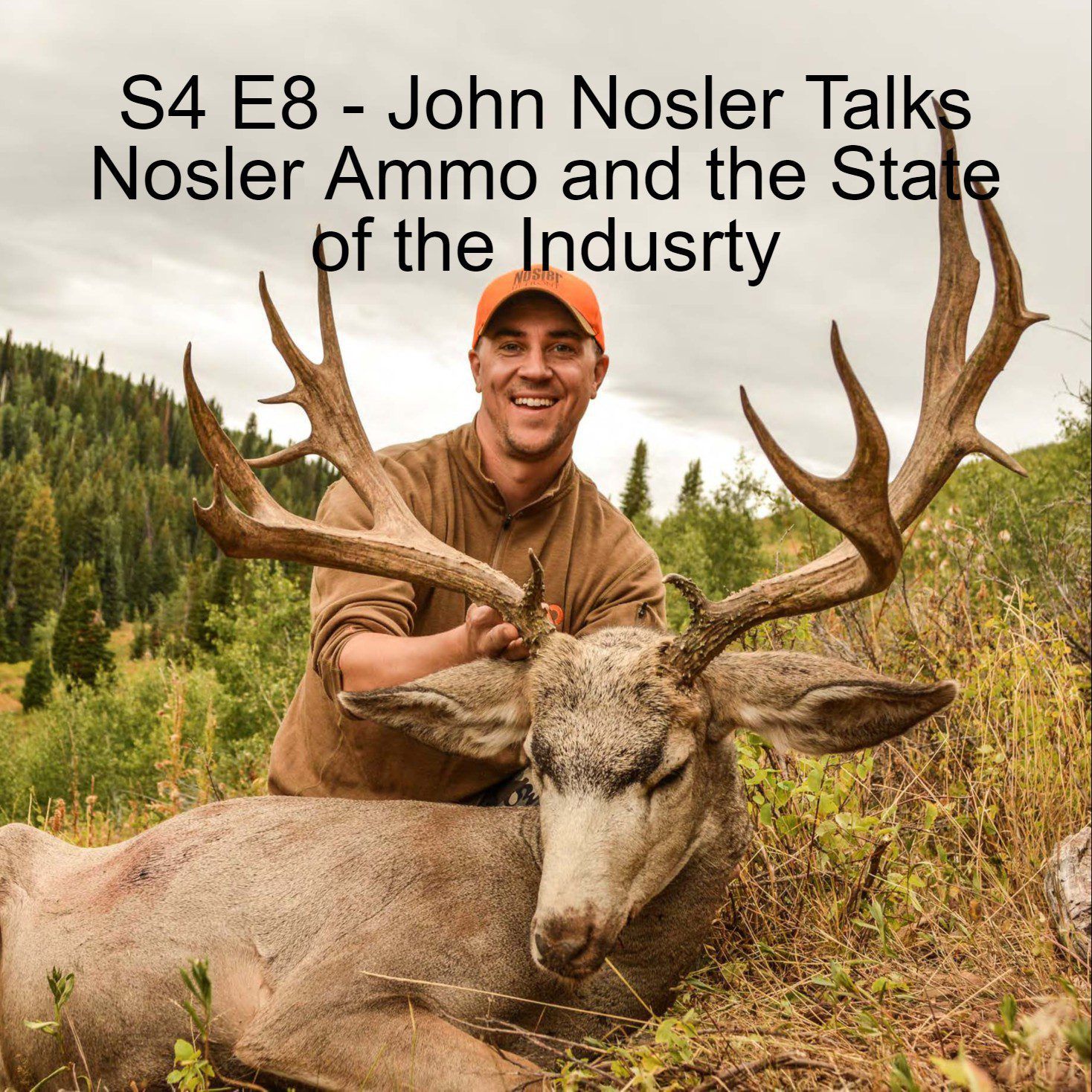 A hunter poses with a mule deer in a forested area.