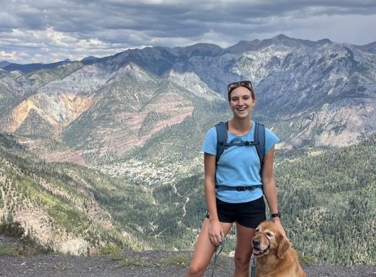 Hiker with a golden retriever enjoying a mountain view.