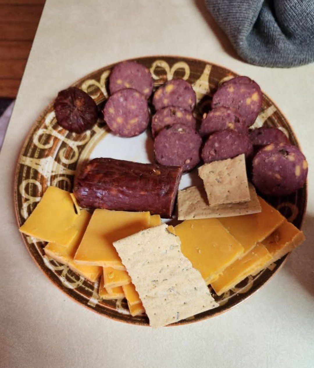 Plate of assorted snacks including sausage, cheese, and crackers.