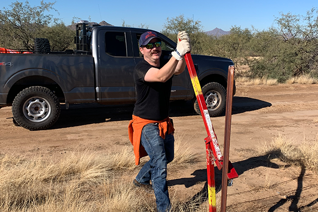 Volunteer installing fence on conservation project.