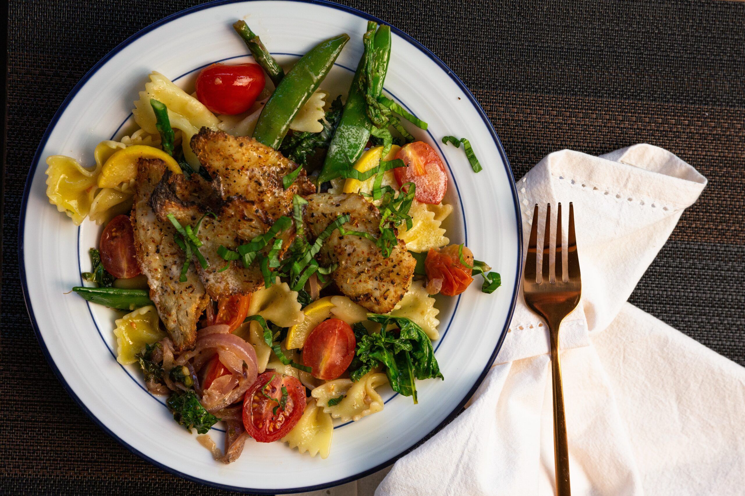 Delicious pasta dish with grilled fish and mixed vegetables.