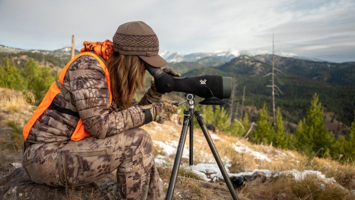 Hunter observing mountains through a spotting scope.
