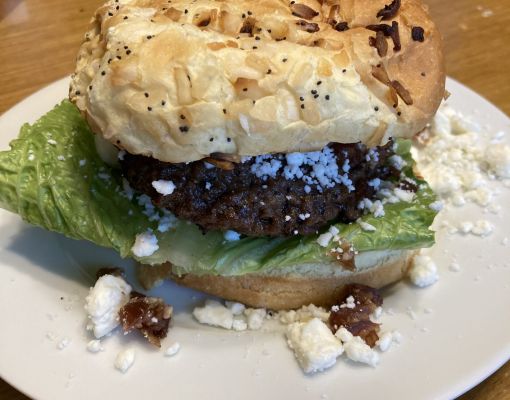 Burger with lettuce, cheese, and an onion bun on a plate.