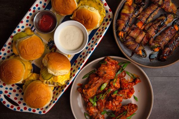 Delicious food platter featuring sliders, hot wings, and bacon-wrapped peppers.