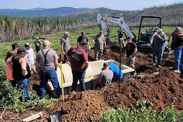 Group of volunteers installing a water trough in a forest setting.