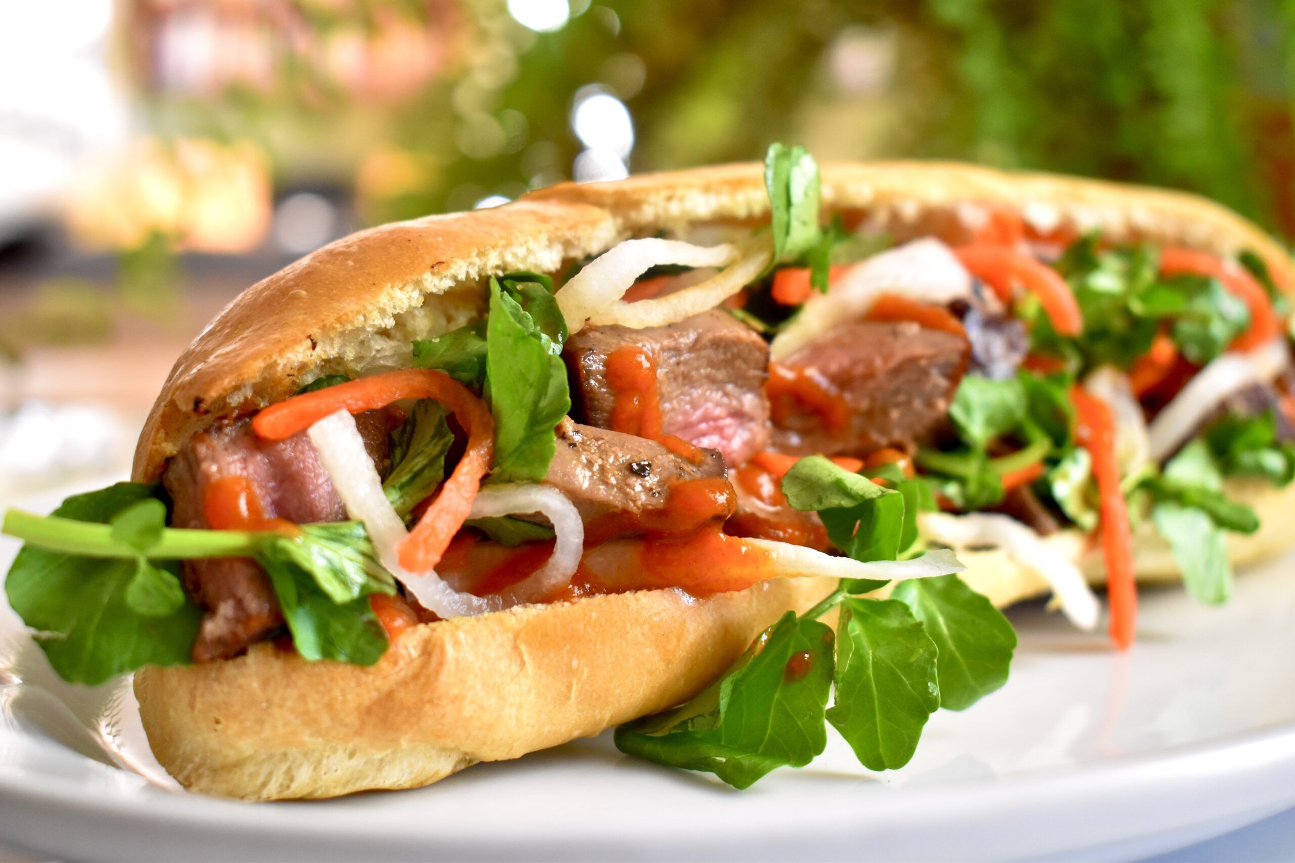 Delicious venison sandwich layered with fresh greens and sauce.