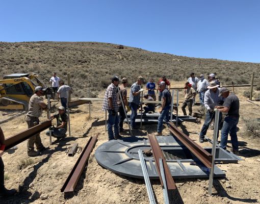 Group of volunteers constructing a fence in sagebrush habitat.