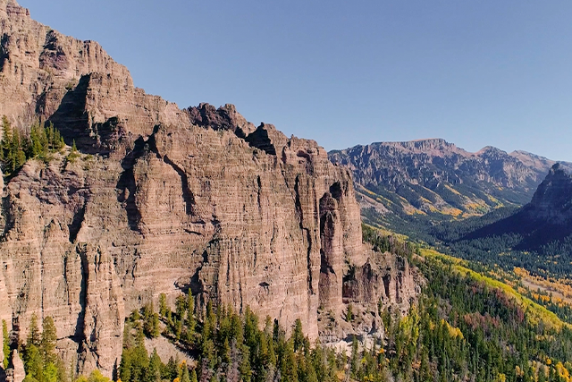 Mountain landscape with rocky cliffs and forested area.