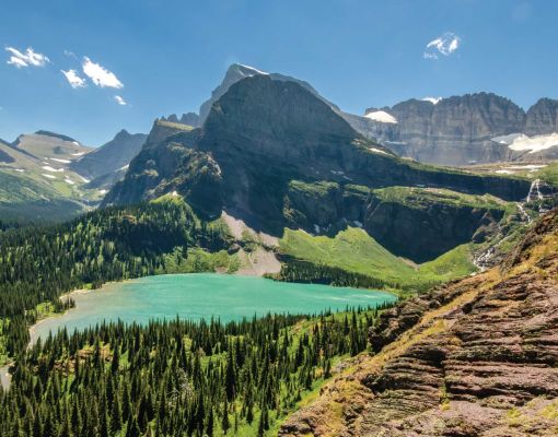A scenic view of a mountain lake surrounded by tall pine trees and rocky peaks.