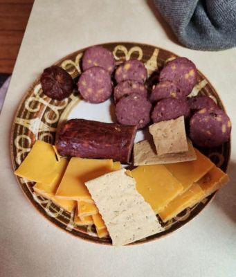 Plate of assorted snacks including sausage, cheese, and crackers.
