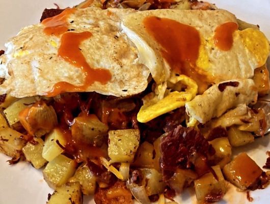 Plate of hash browns topped with eggs and sauce