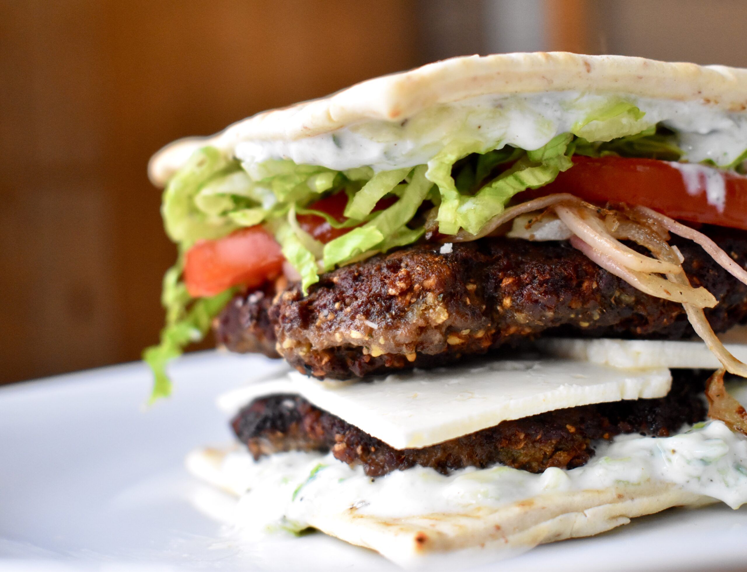 Gourmet burger featuring layers of vegetables and sauce.