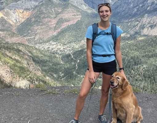 Hiker with a golden retriever enjoying a mountain view.