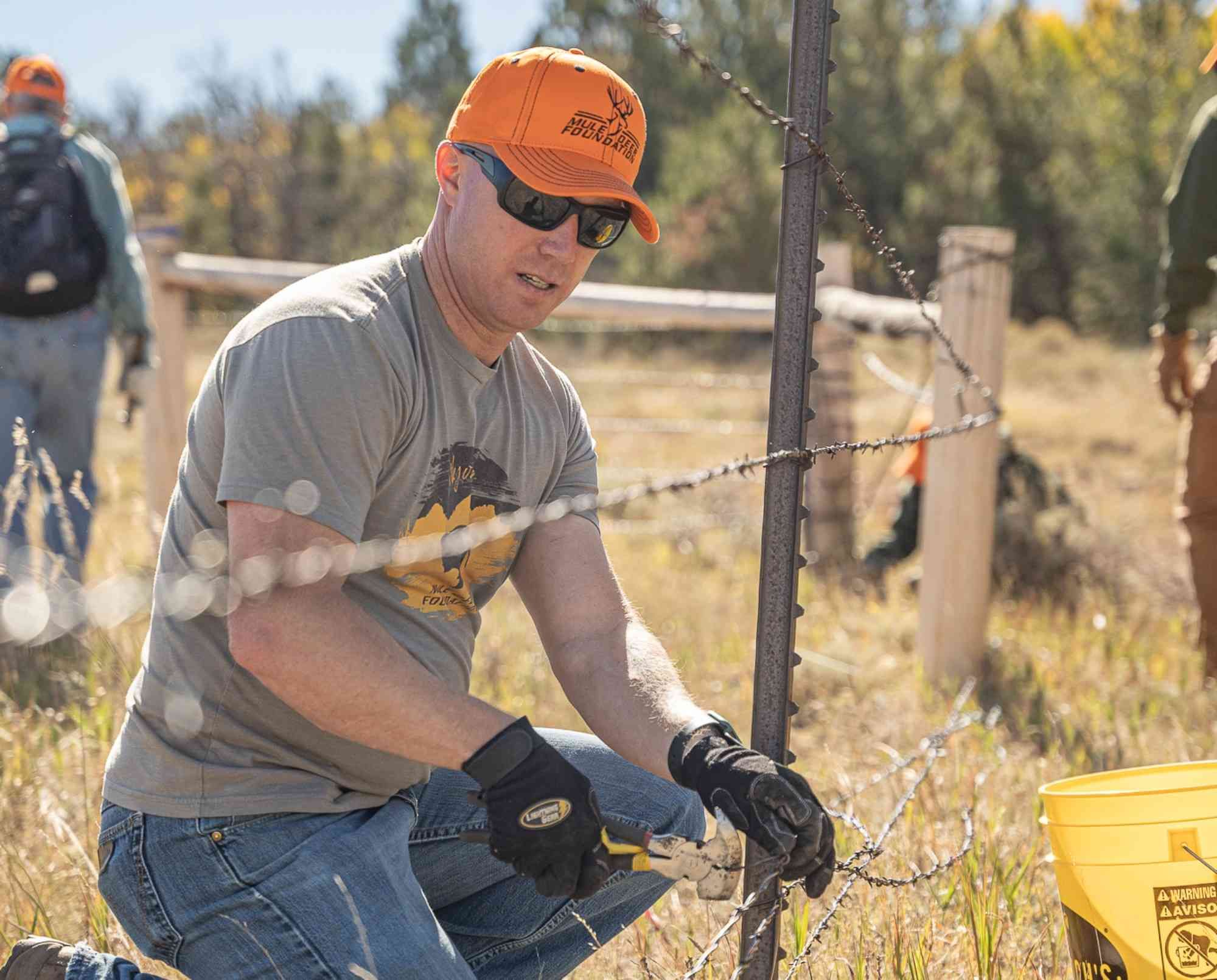 Volunteer repairing fence during habitat restoration work for Mule Deer Foundation.
