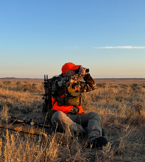 Hunter observing the landscape at sunset in camouflage gear