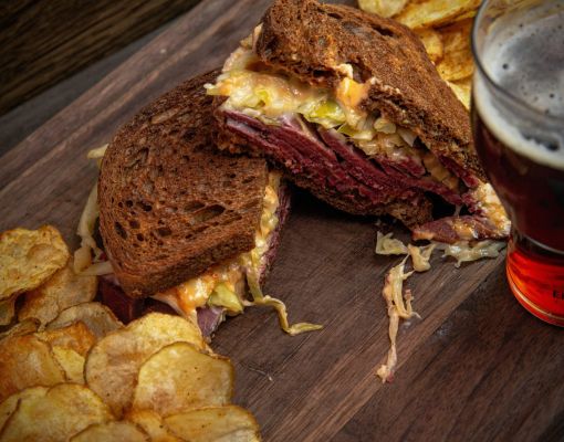 Close-up of corned beef sandwich with chips and beer